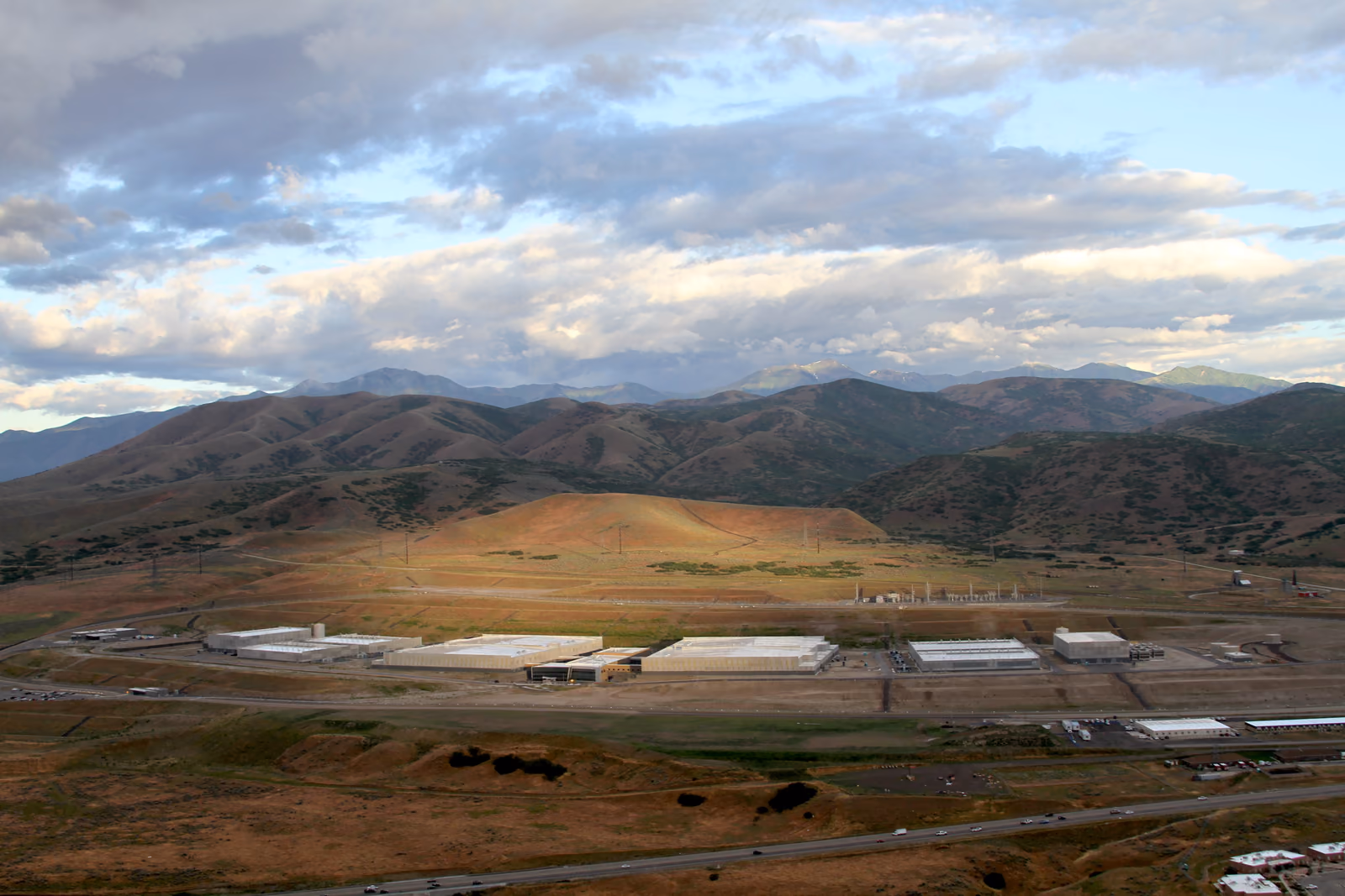 Aerial view of a large data-center campus with several long halls, support buildings, roads, and electrical infrastructure.